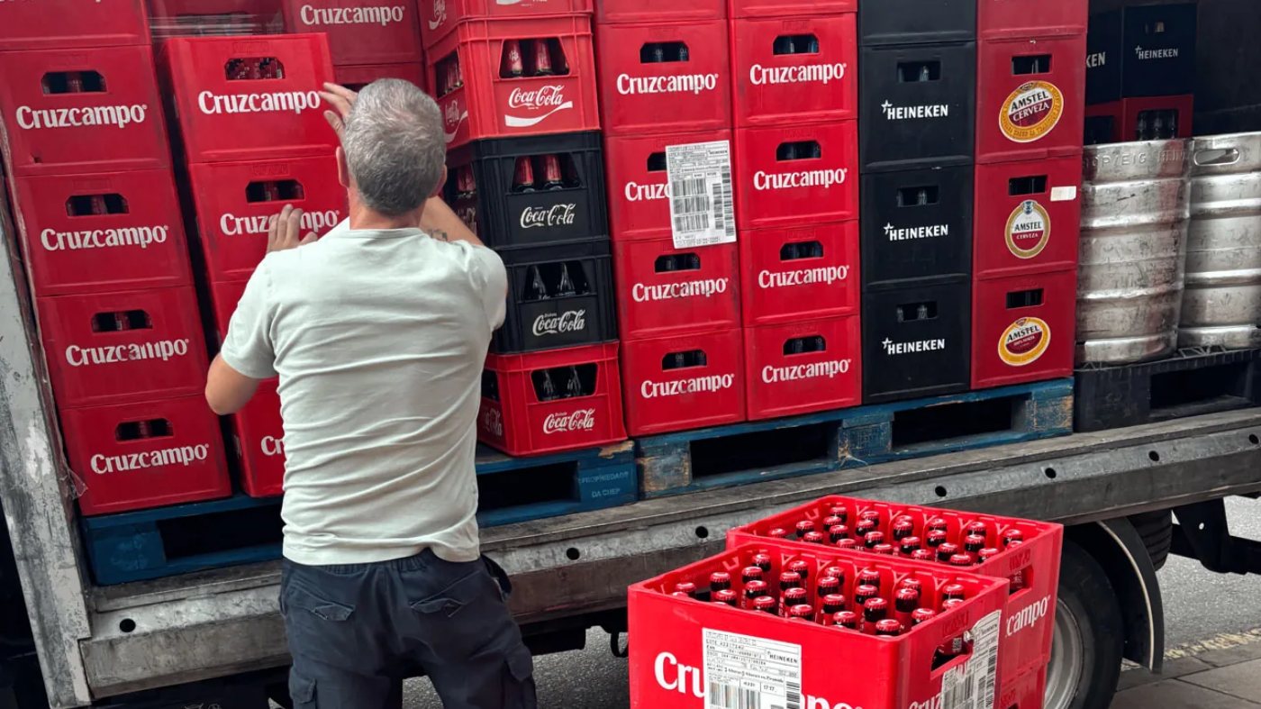 Un repartidor coloca cajas de refrescos y barriles de cerveza en la caja del camión